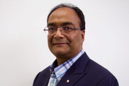 Mukesh Haikerwal smiles while dressed in a business suit.