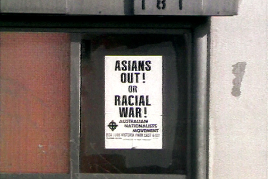 A white poster with an anti-Asian message stuck on the front of a bus stop.
