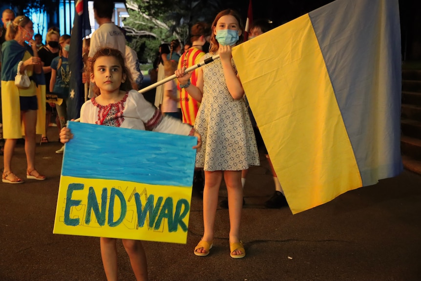 A child holds an anti-war sign at a Ukraine vigil in Darwin.