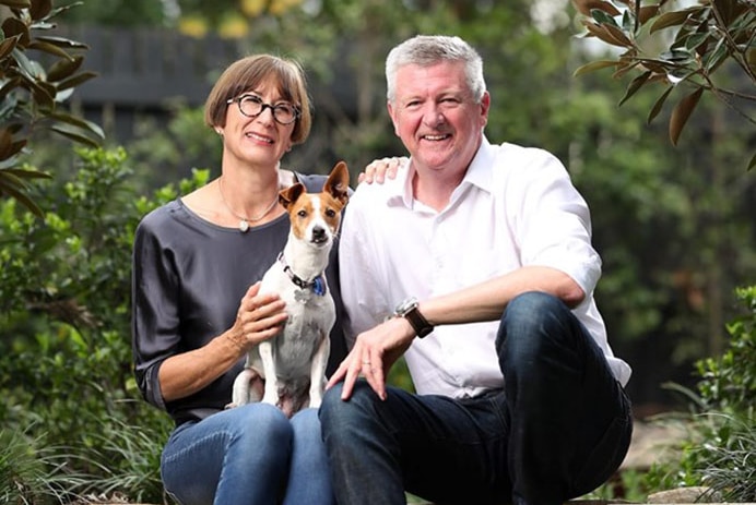 Patrick Condren with his wife Margaret and their dog, sit on a wall in a garden.