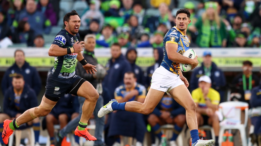 Parramatta Eels' Dylan Brown runs with the ball in front of Canberra Raiders' Jordan Rapana.