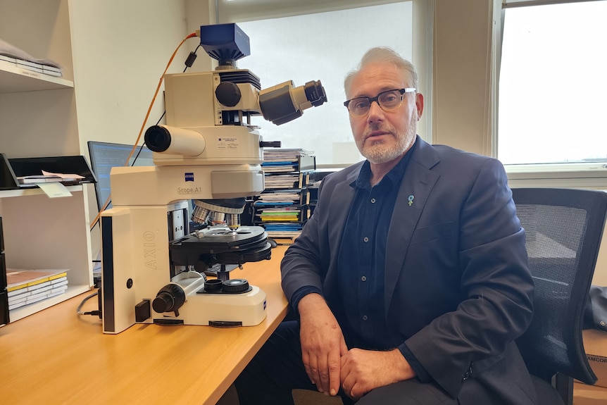 Michael next to a microscope.