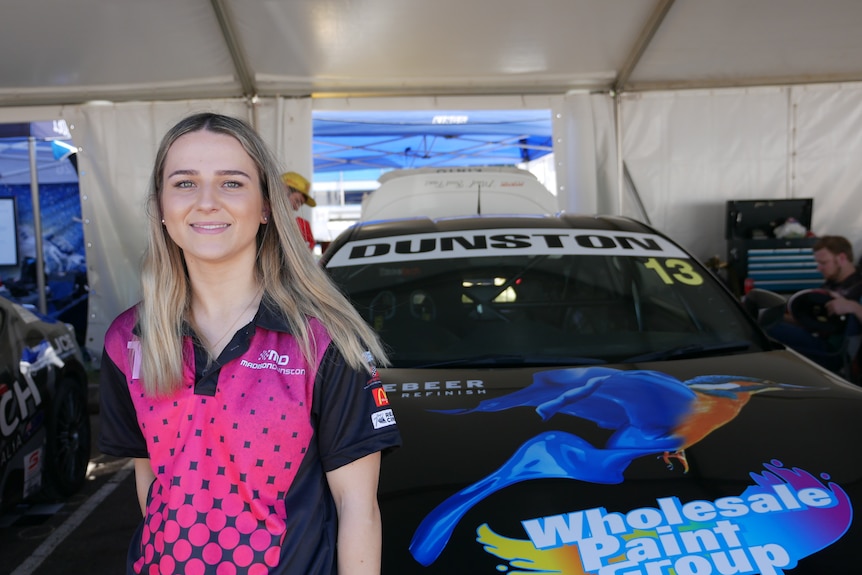 Femme debout devant une voiture de course