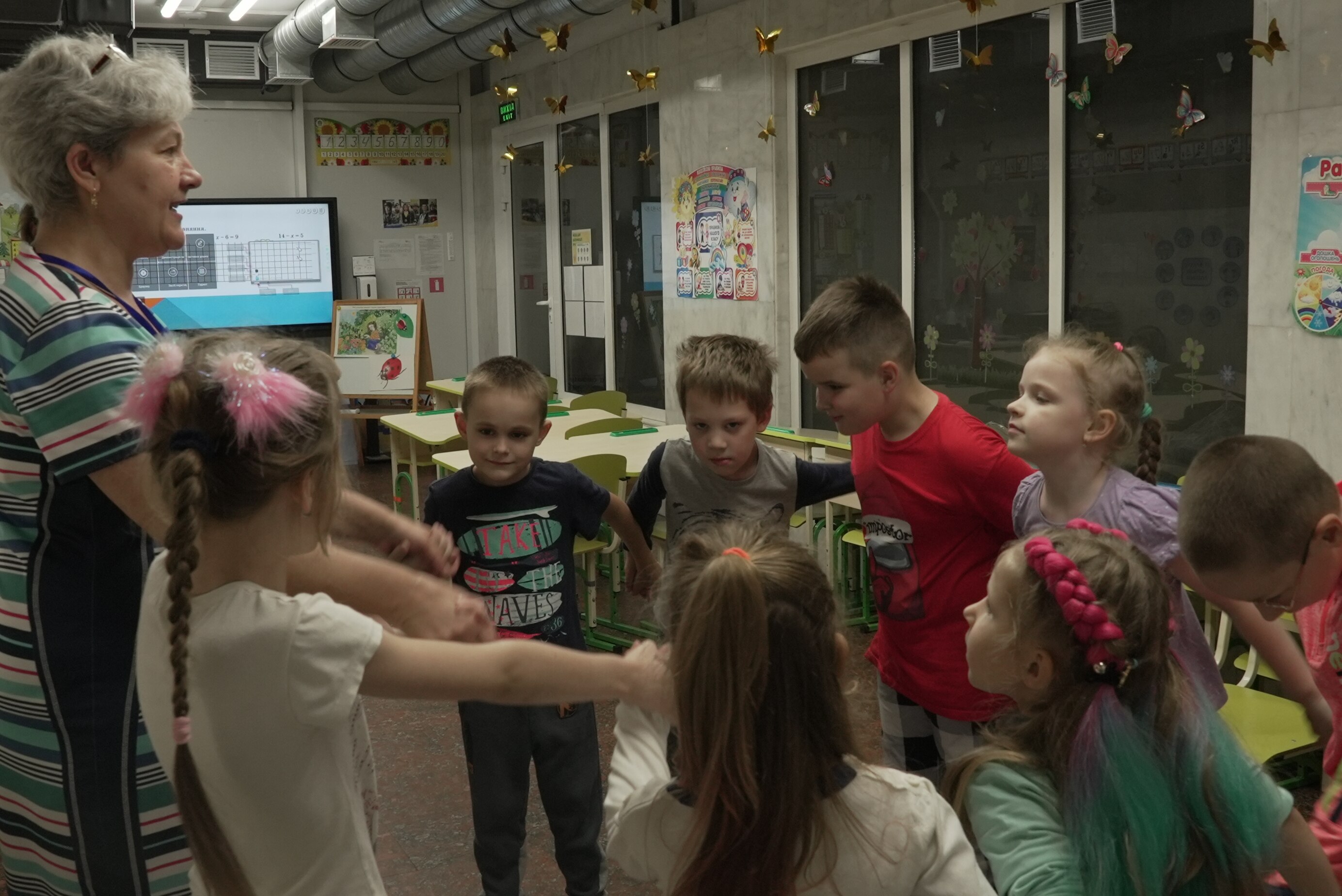 Children holding hands in a circle with a teacher 