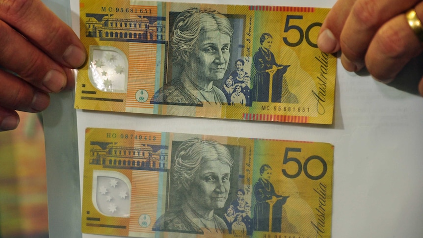 Police show real $50 note on top, fake $50 note on bottom