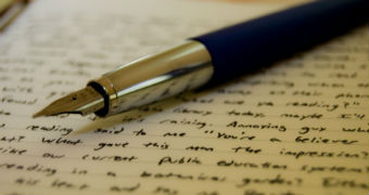 A pen sits on a page of handwritten writing.