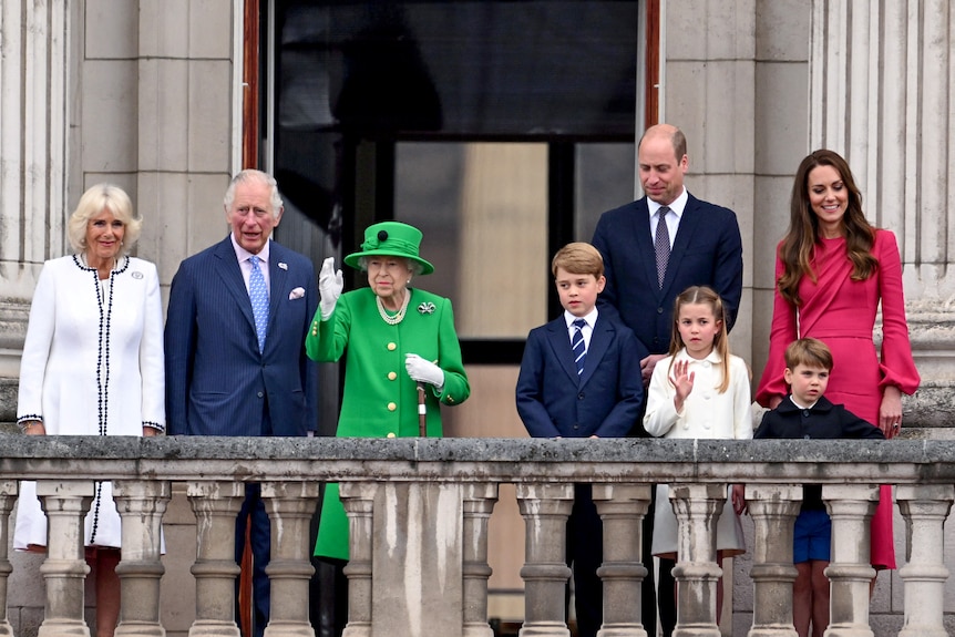 The royal family stands on the balcony and waves to the public.