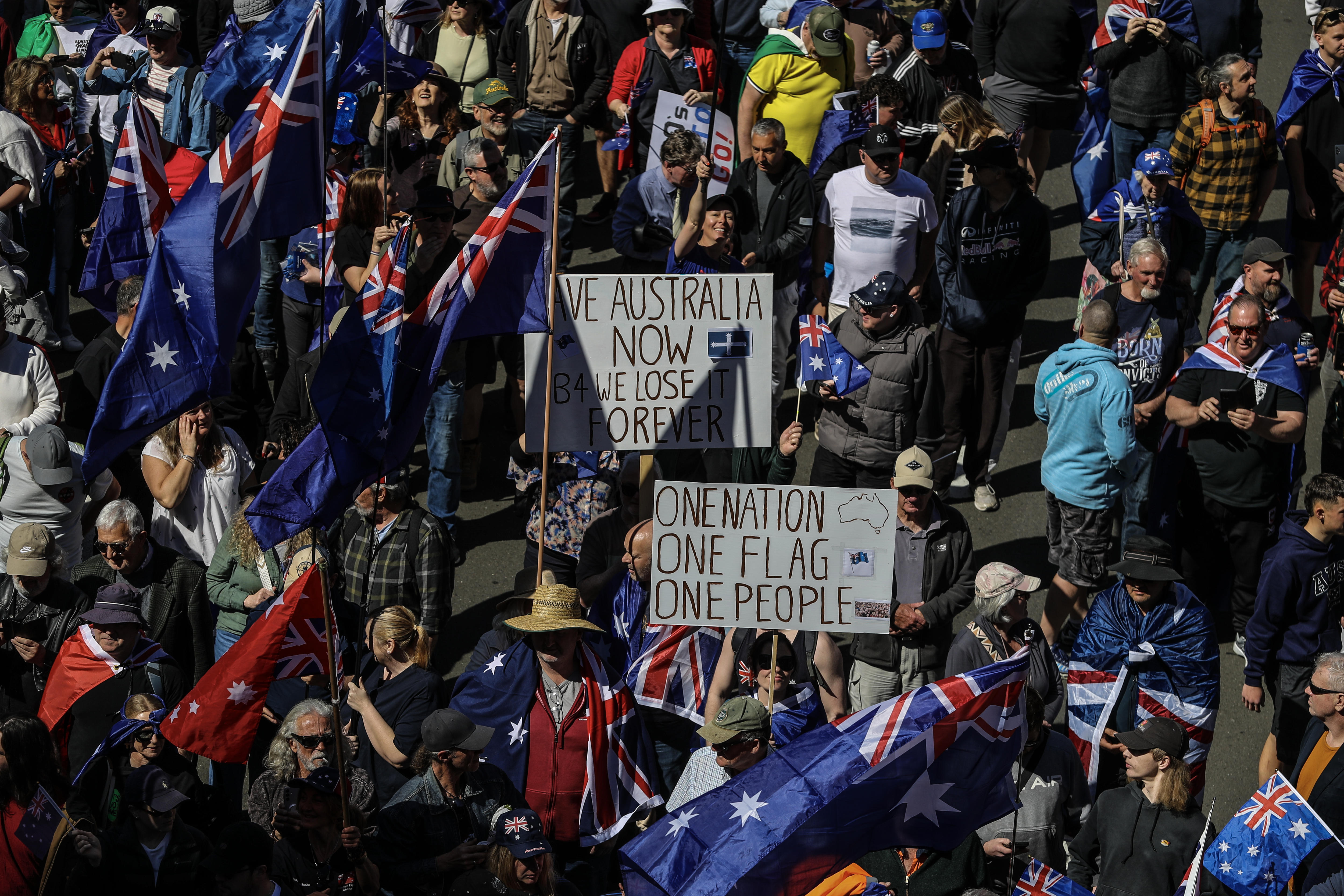 A group of protesters hold placards and wave the Australian flag during a rally in Sydney.