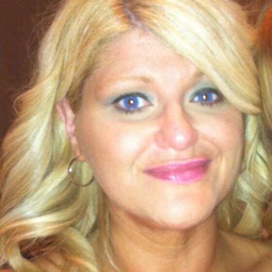 A close up photo of a smiling woman with long blonde hair and blue eyes