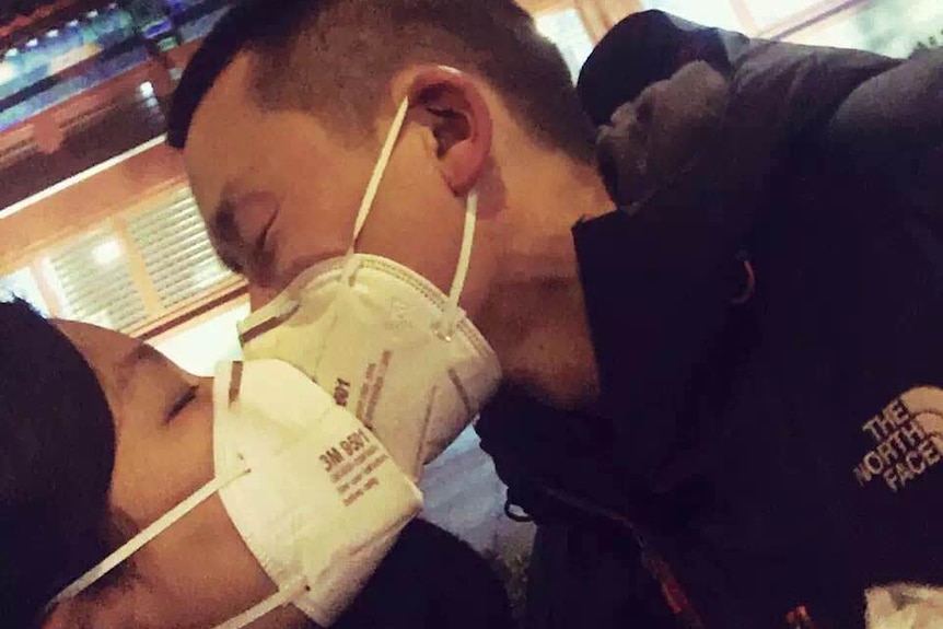 Chinese couple kisses through face masks