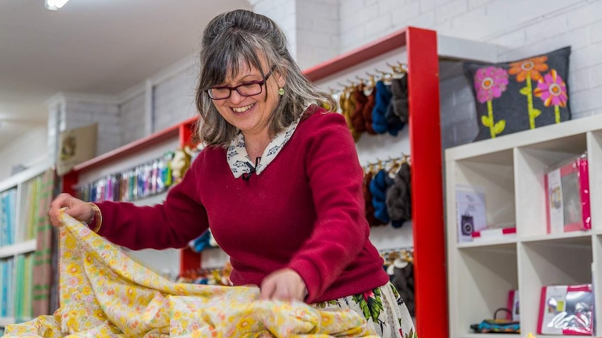 Woman measuring length of material in haberdashery shop.