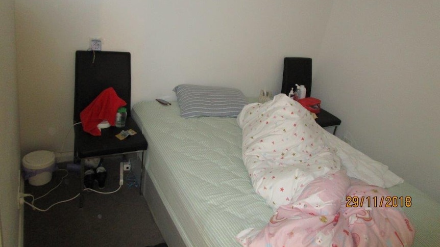 A room inside an illegal brothel ACT Policing shut down, with bed, chair, money and bin among the objects inside.