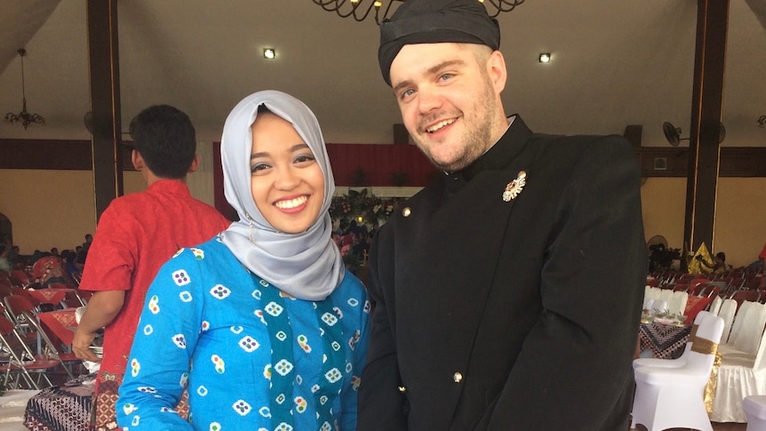 A woman wearing a traditional Indonesian outfit next to man wearing the male version of the traditional outfit.