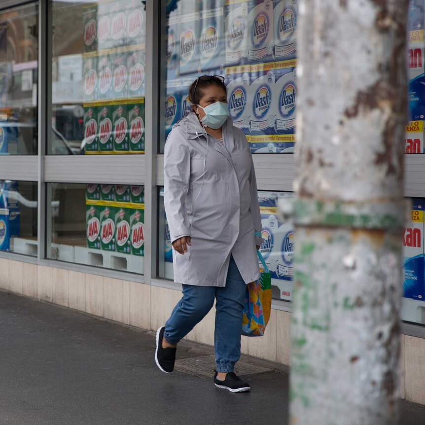 A woman walks past a shop window filled with washing detergent