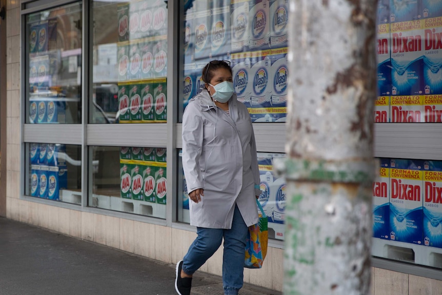 A woman walks past a shop window filled with washing detergent