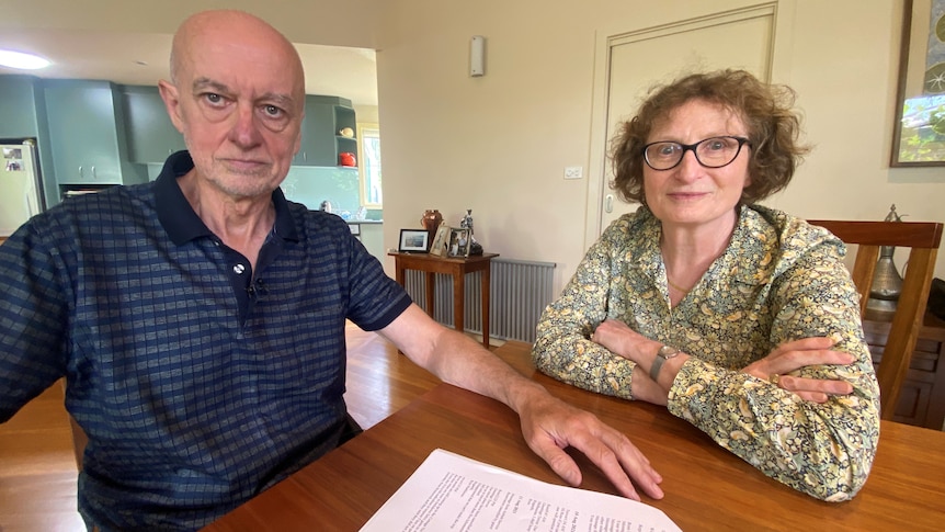 A couple sits by a table.