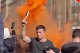 A young man carrying an orange flare