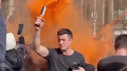 A young man carrying an orange flare