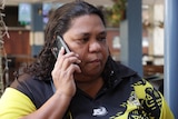 An Indigenous woman talks on the phone outside a hotel.