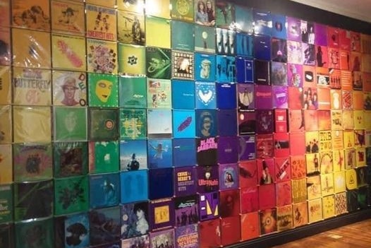 A wall full of colourful record covers, green, blue, pink and yellow.