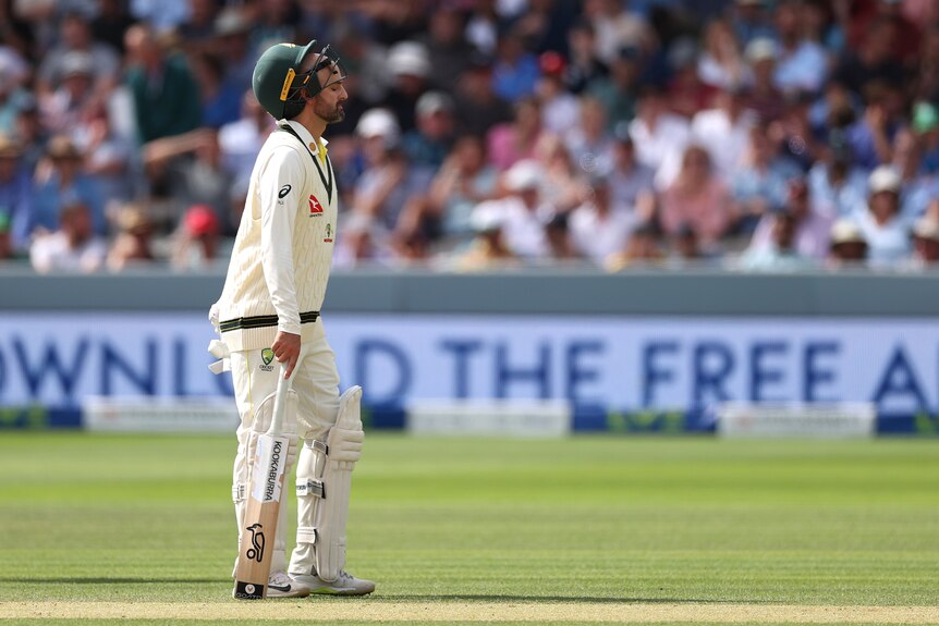 Australia batter Nathan Lyon walks on the field during a Test with his helmet pushed back on his head.