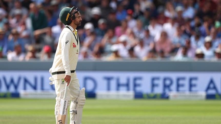 Australia batter Nathan Lyon walks on the field during a Test with his helmet pushed back on his head.
