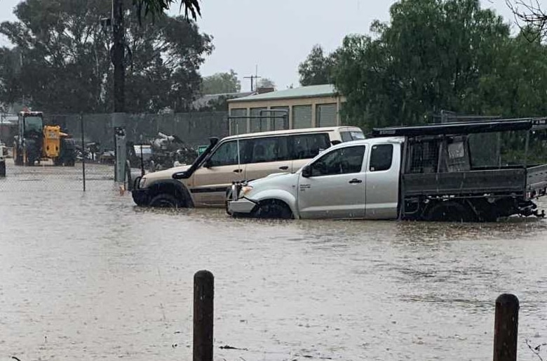 A car park is flooded with water almost up to the top of car tyres.