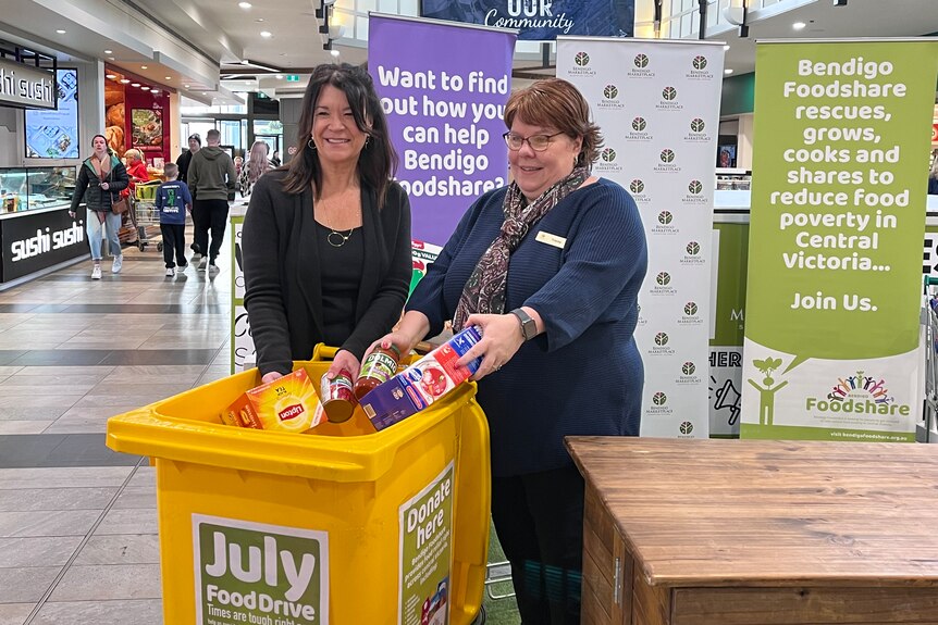 Two people with a bin filled with donated food.