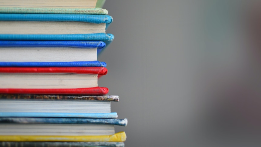 A neat stack of coloured books, viewed from their spines.