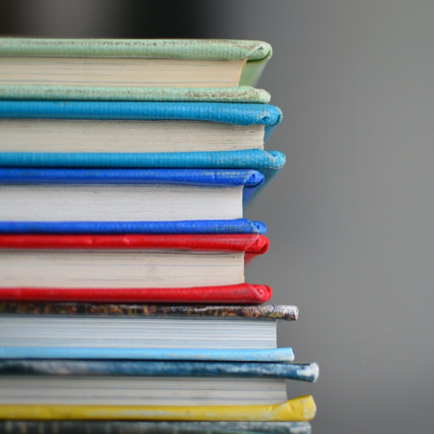 A neat stack of coloured books, viewed from their spines.