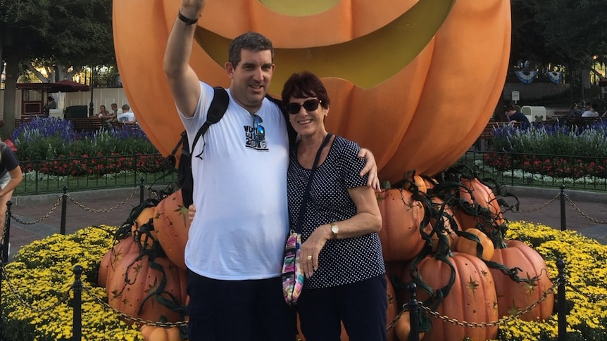 Man and woman in front of Disney carved pumpkin