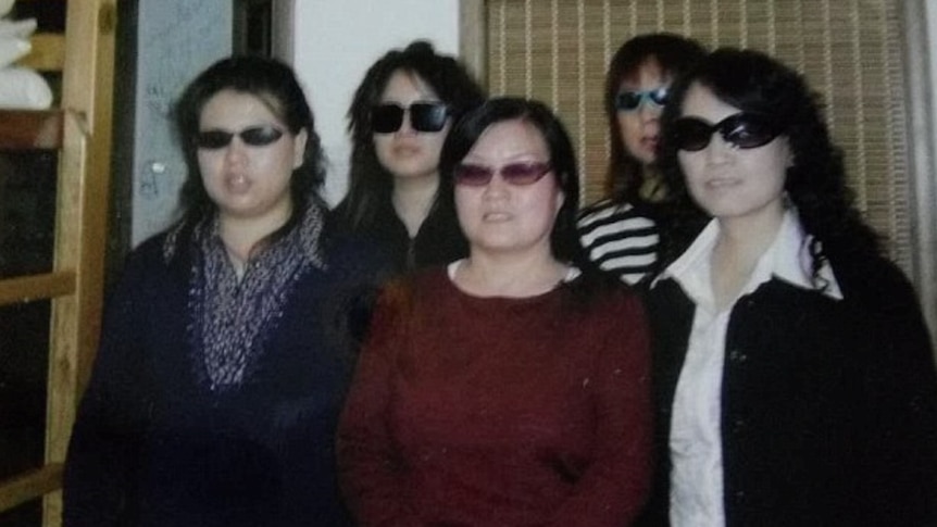 A group of Chinese women stand together wearing sunglasses