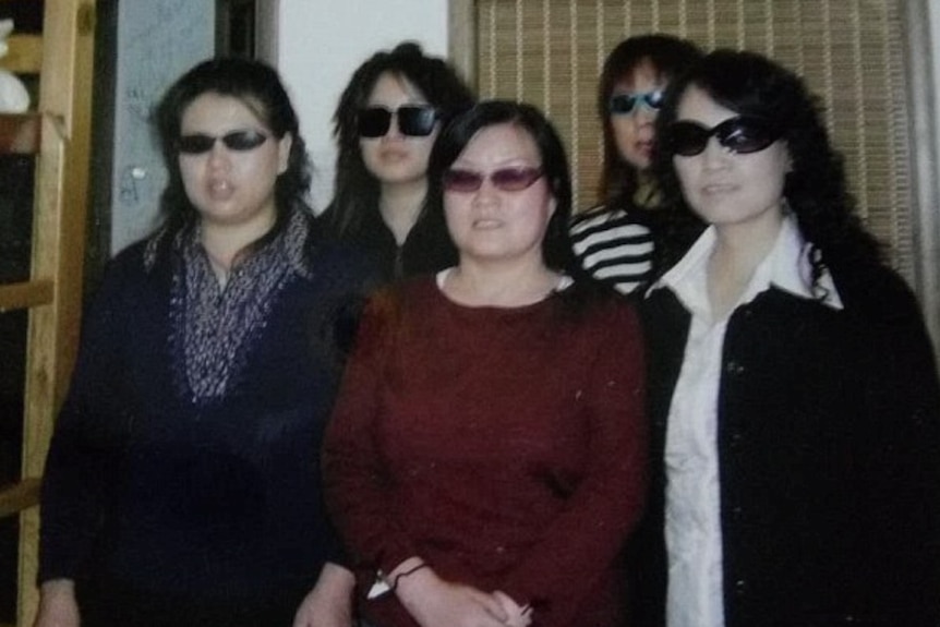 A group of Chinese women stand together wearing sunglasses
