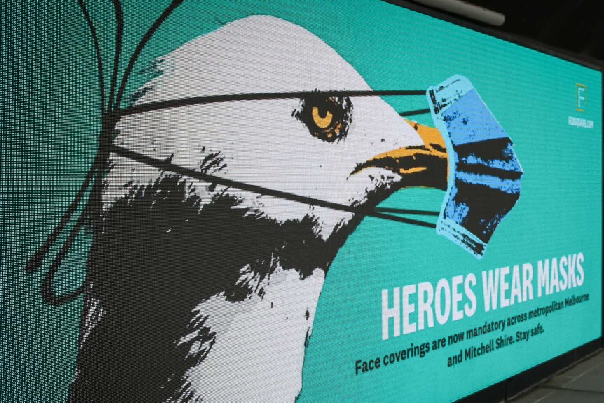 A photo of a billboard showing a seagull wearing a mask.
