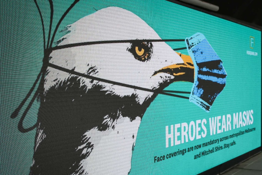 A photo of a billboard showing a seagull wearing a mask.