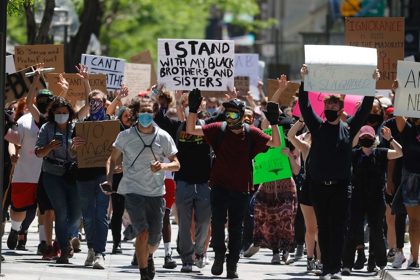 Participants walk with their hands in the air down the 16th Street Mall during a protest over the death of George Floyd.