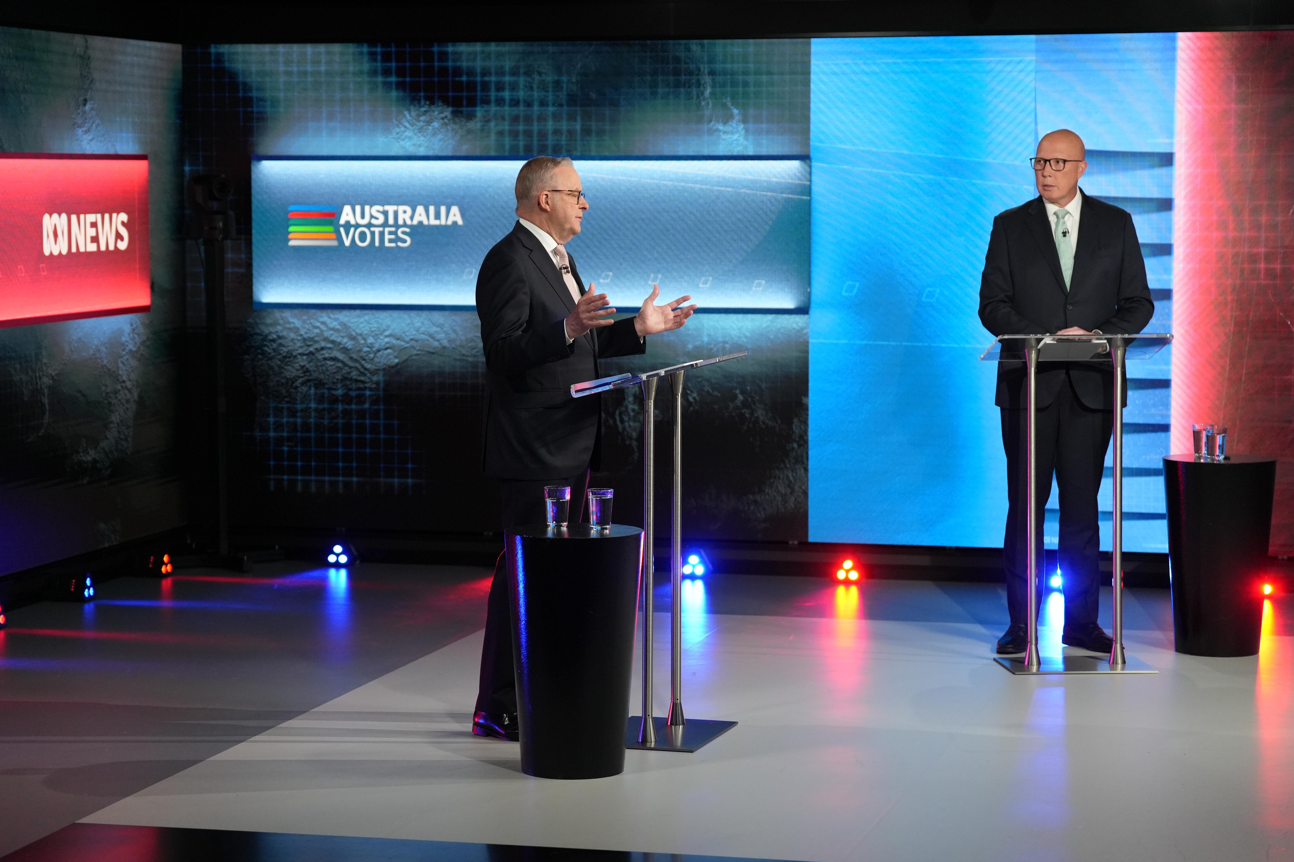 Albanese and Dutton stand at separate podiums on a tv set.