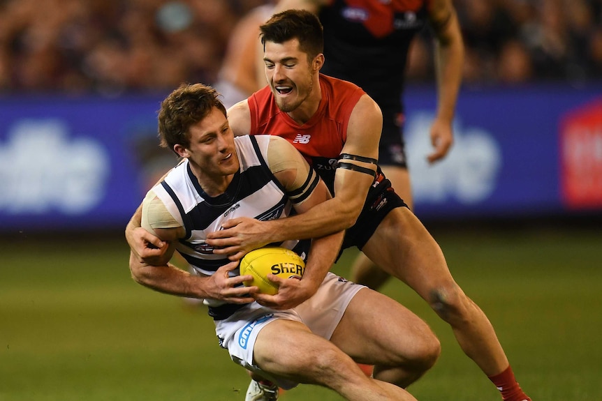 Jed Bews (L) of the Cats is tackled by Bayley Fritsch of the Demons.