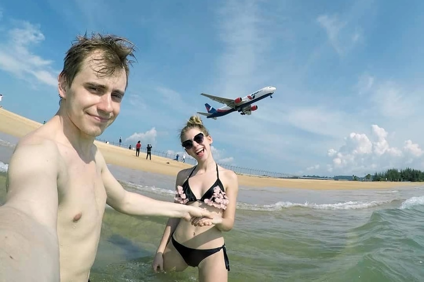 A couple at Mai Khao beach with a plane overhead