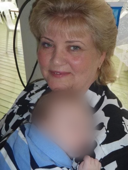 A photo of Rosemarie Campbell holding a baby with a blurred face. 