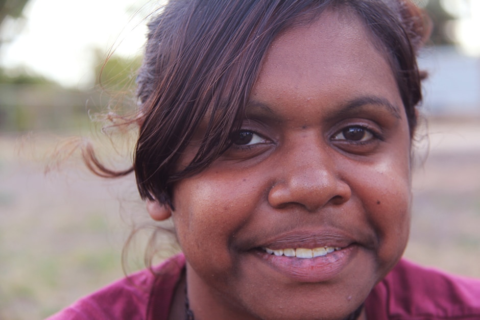 A young Aboriginal woman looks directly at the camera