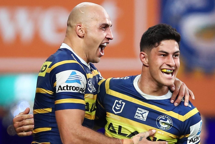 Two Parramatta Eels players celebrate a try being scored against the Brisbane Broncos.