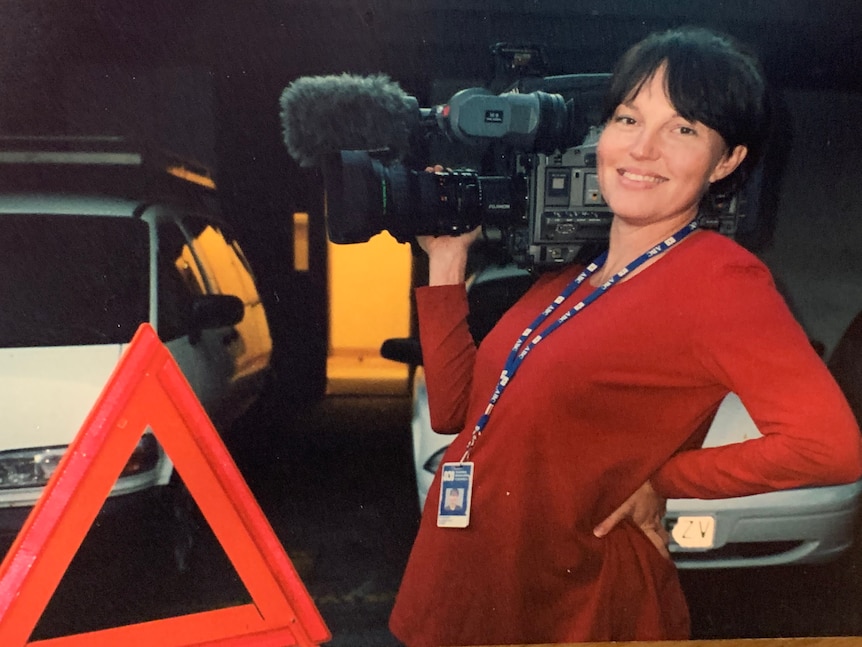 Woman holding camera on shoulder while leaning back showing pregnant belly.