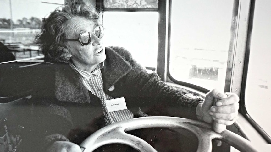 A black-and-white photo of author Thea Astley wearing sunglasses while driving the Writers Train.