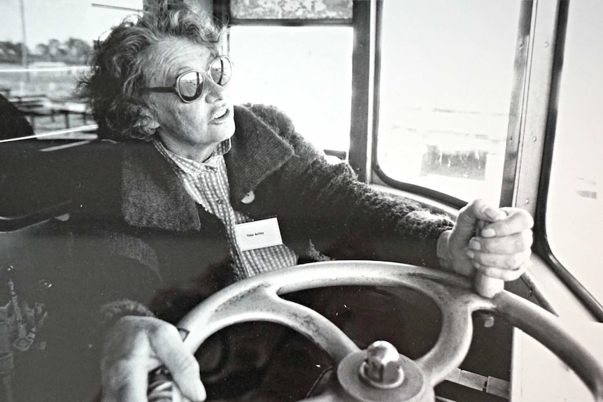 A black-and-white photo of author Thea Astley wearing sunglasses while driving the Writers Train.