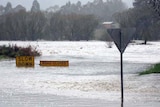 Two road signs disappear under floodwaters