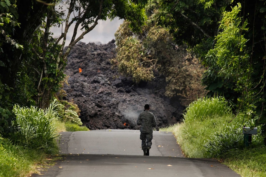 An Air Force member stands near a lava flow.