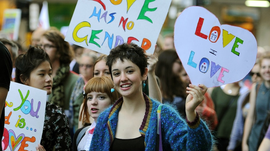 Young women hold signs at same-sex marriage rally