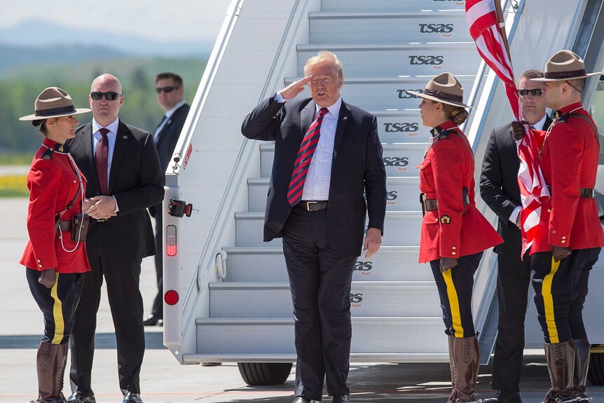 Trump is seen saluting as he arrives at Canadian Forces Base.