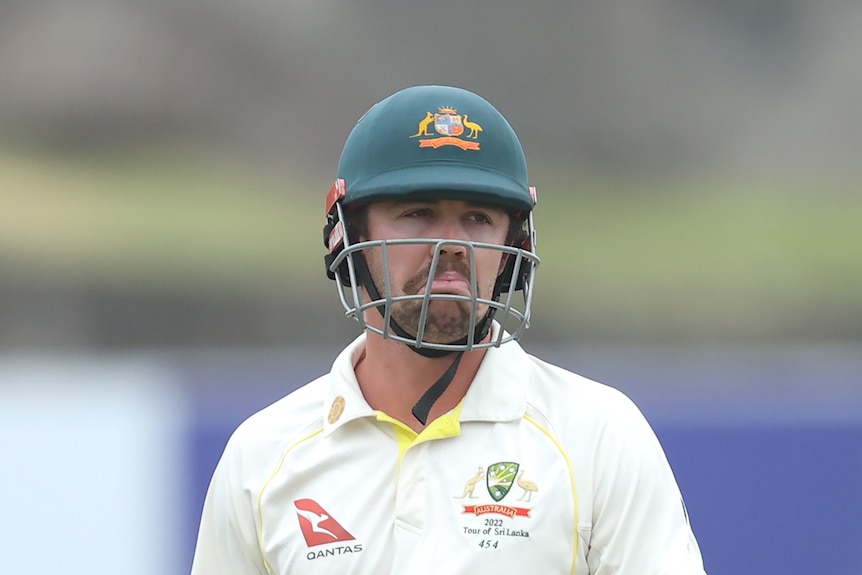 Travis Head has a sad look on his face with his mouth turned down wearing a cricket batting helmet